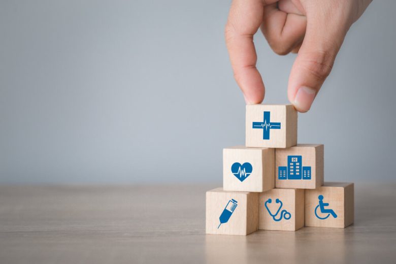 Hand holding several wood cubes about healthcare - Cost-U-Less - cheap auto insurance in California