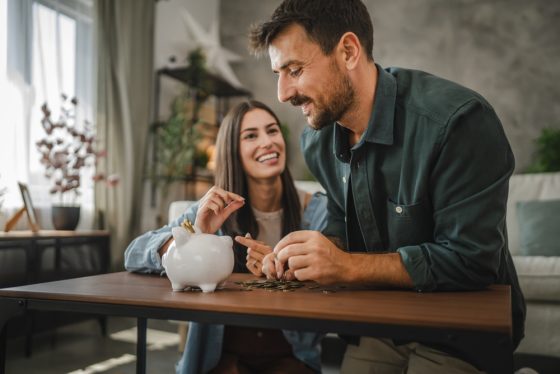 Adult couple save money coins in the piggy bank at home - Cost-U-Less - cheap auto insurance in California