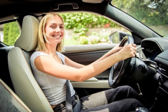 Young teenager sits behind the wheel of a car.