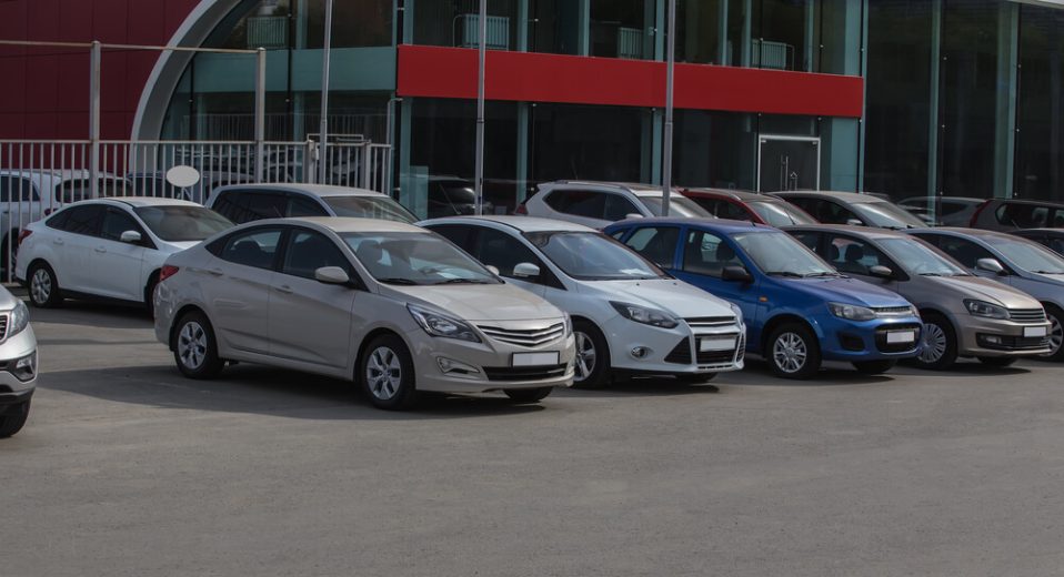 A line of used cars at a dealership - cheap car insurance in California.