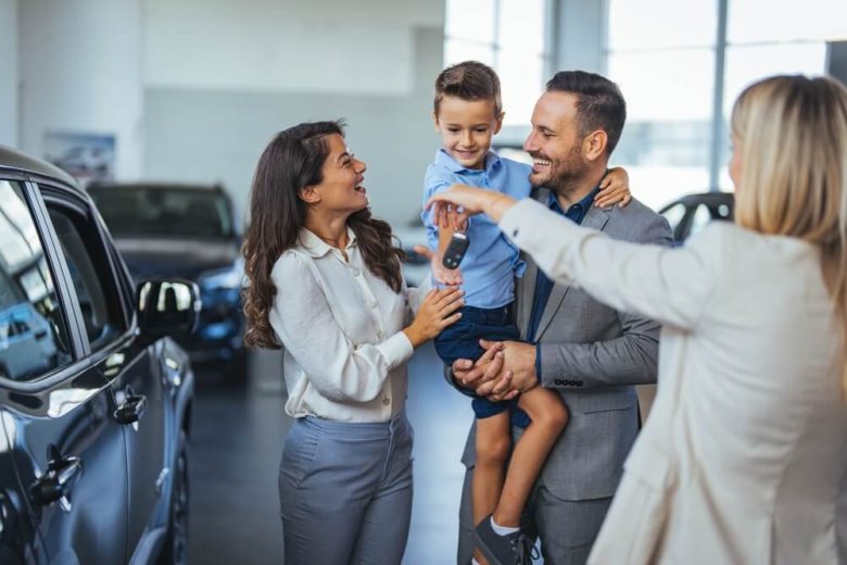 Family with small child getting the keys to their new car at the dealership - cheapest car insurance in California.