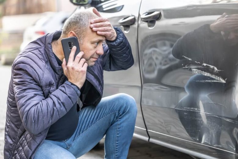 Man on the phone to insurance company after discovering someone has hit his car and left the scene - cheap car insurance in California.