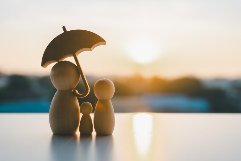 Small wooden dolls representing a family under an umbrella.